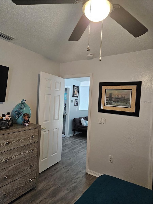 bedroom featuring ceiling fan, dark hardwood / wood-style flooring, and a textured ceiling