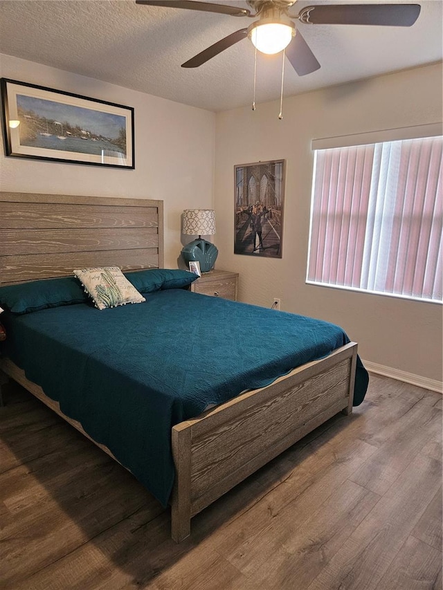 bedroom featuring ceiling fan, wood-type flooring, and a textured ceiling