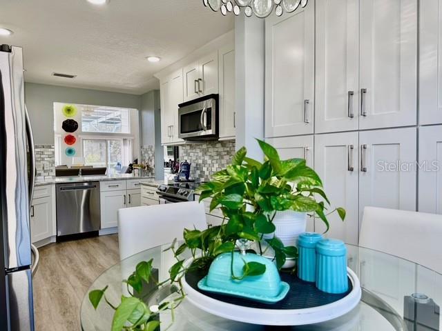 kitchen featuring white cabinets, appliances with stainless steel finishes, decorative backsplash, and light hardwood / wood-style floors