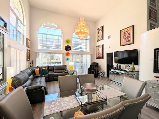 dining room featuring a notable chandelier, a high ceiling, visible vents, and wood finished floors