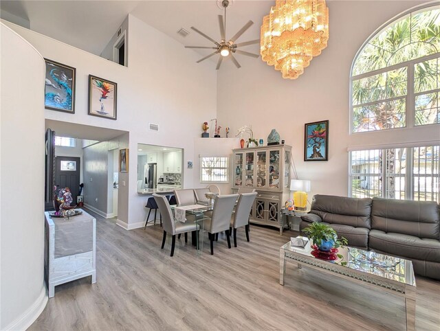 dining room with ceiling fan with notable chandelier, wood finished floors, visible vents, and baseboards