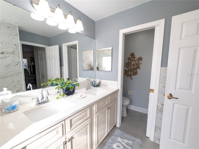 bathroom with toilet, double vanity, baseboards, and a sink