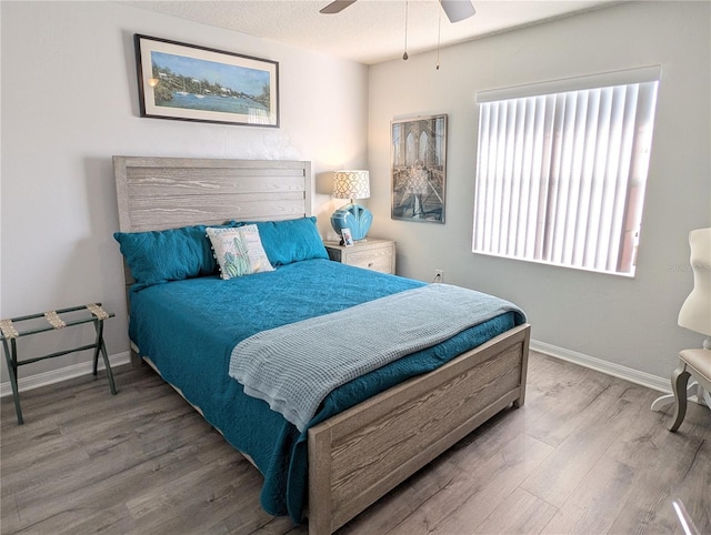 bedroom with wood finished floors, a ceiling fan, and baseboards