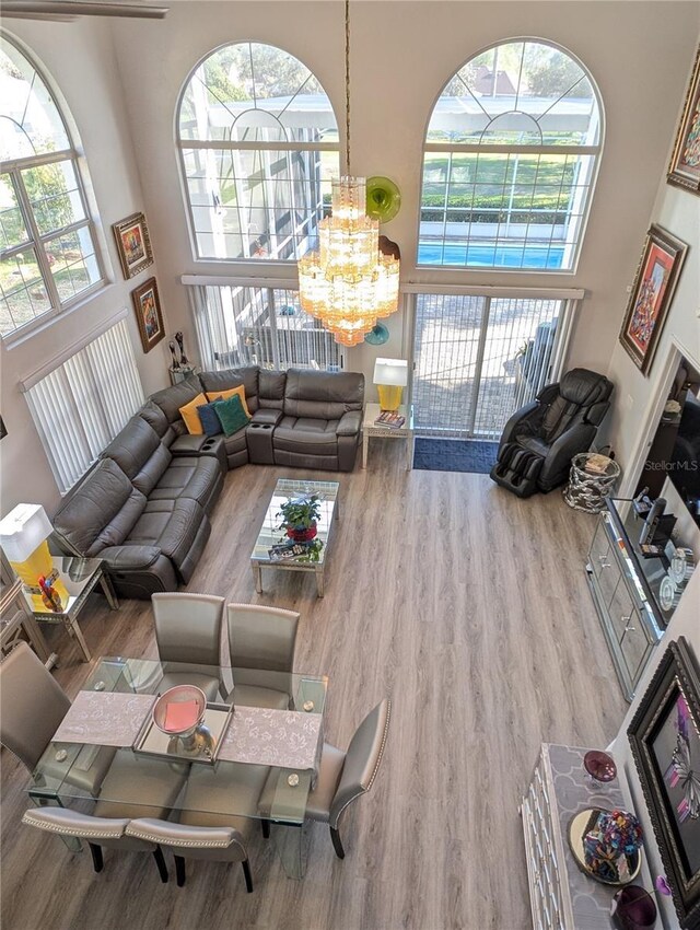 living room with an inviting chandelier, a high ceiling, and wood finished floors