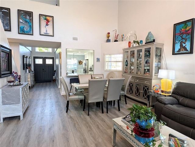 dining area featuring a high ceiling, wood finished floors, and visible vents