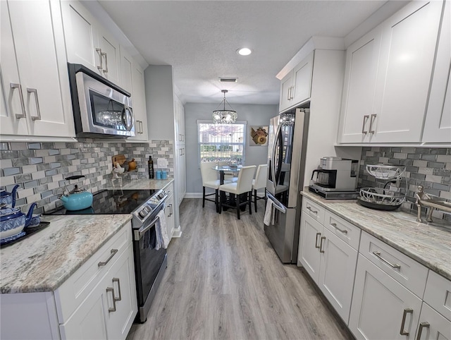 kitchen with light wood finished floors, visible vents, white cabinets, appliances with stainless steel finishes, and backsplash