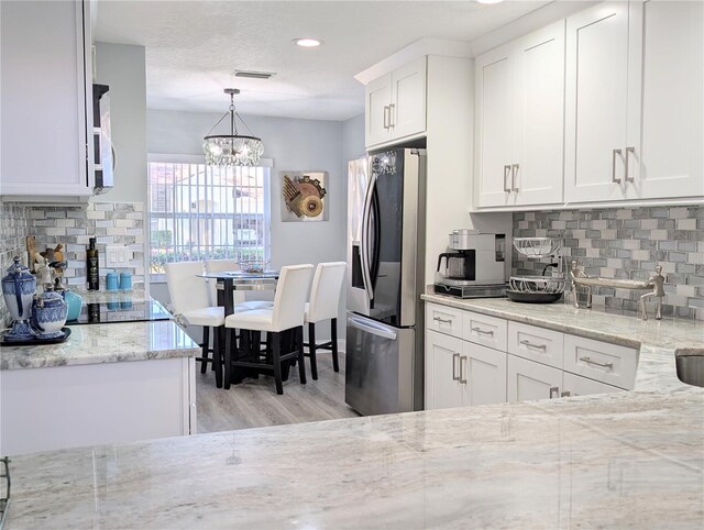 kitchen featuring light wood finished floors, visible vents, decorative backsplash, stainless steel fridge with ice dispenser, and white cabinetry