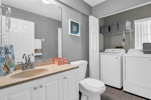 bathroom with vanity, washing machine and dryer, and toilet