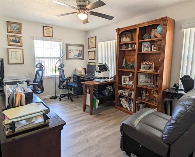 home office with a textured ceiling, ceiling fan, light wood-style flooring, and baseboards