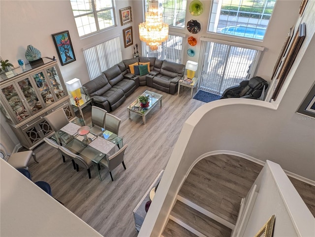 living area with a high ceiling, a chandelier, and wood finished floors