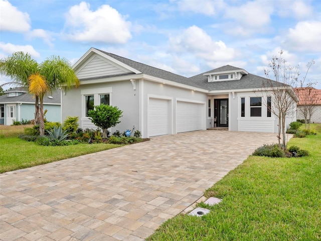 view of front of property featuring an attached garage, a shingled roof, decorative driveway, and a front yard