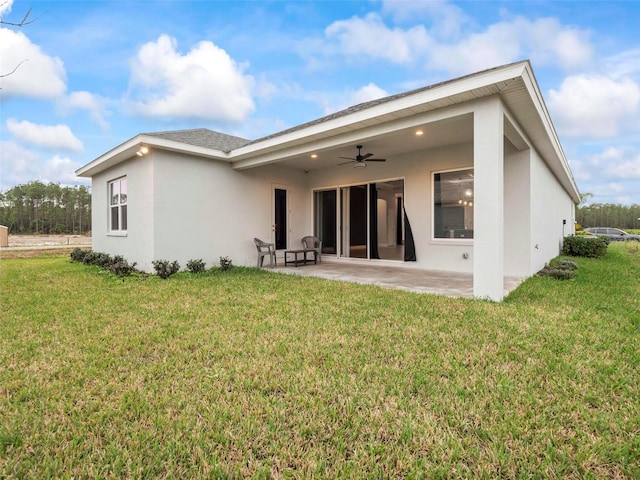 rear view of property with a yard, stucco siding, a ceiling fan, and a patio