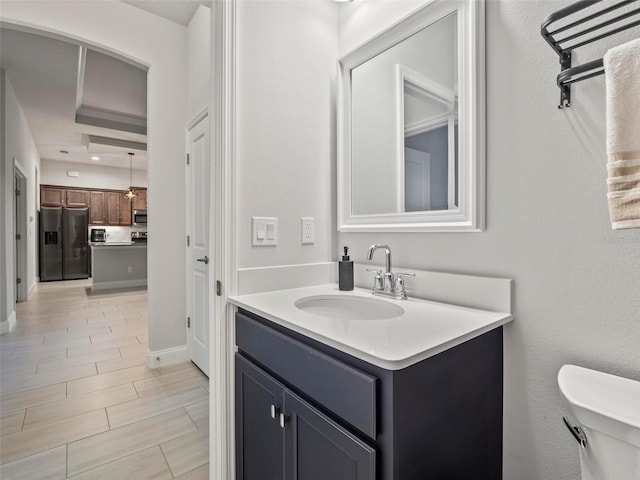 half bathroom with toilet, vanity, and baseboards