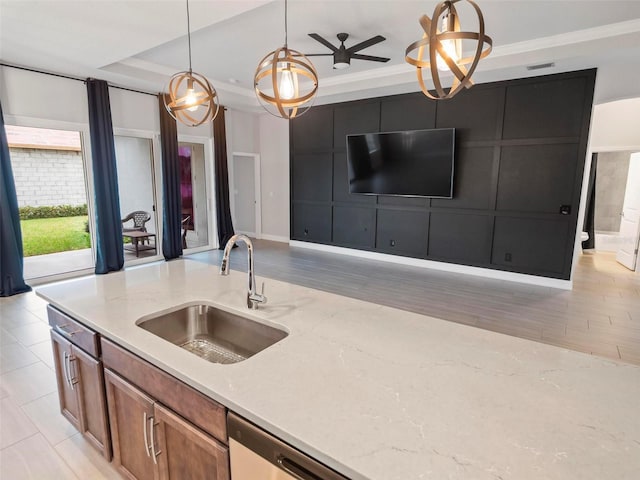 kitchen with pendant lighting, a sink, open floor plan, a raised ceiling, and light stone countertops