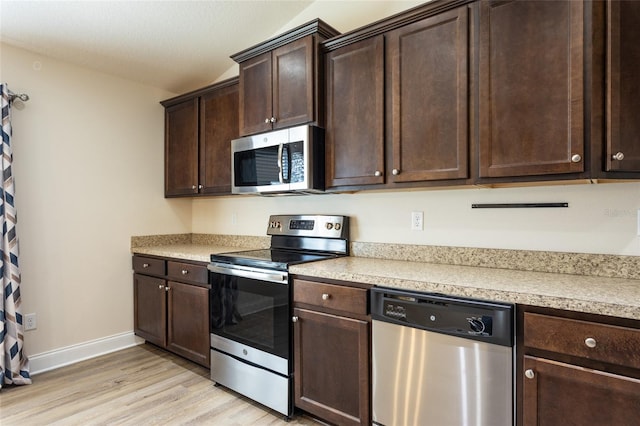 kitchen with dark brown cabinetry, lofted ceiling, stainless steel appliances, and light wood-type flooring