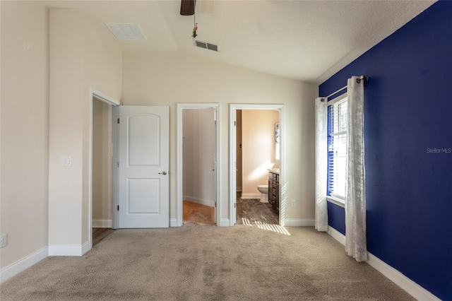 unfurnished bedroom featuring vaulted ceiling, connected bathroom, ceiling fan, light carpet, and a closet