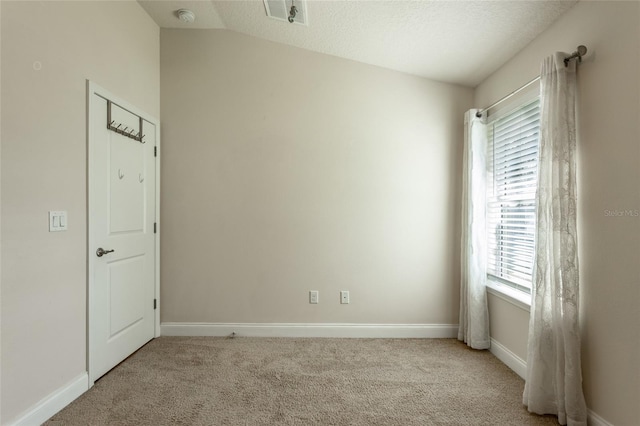 spare room with light carpet and vaulted ceiling