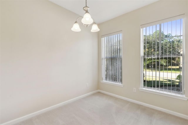 carpeted spare room with an inviting chandelier