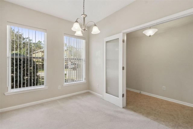 spare room featuring light carpet and a chandelier