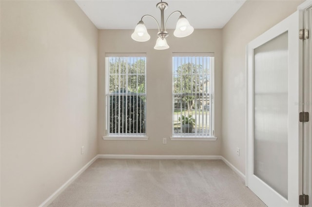 unfurnished room with light colored carpet and a chandelier