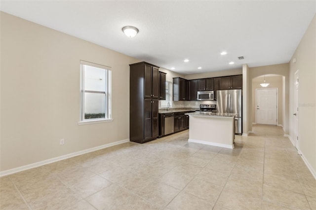 kitchen with a center island, sink, dark brown cabinetry, stainless steel appliances, and light tile patterned floors