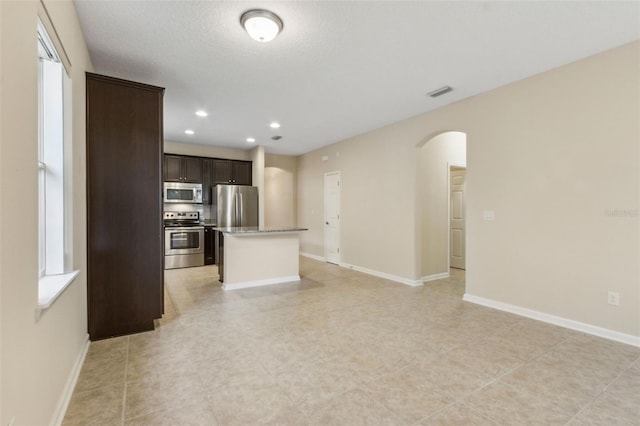 kitchen with dark brown cabinets, a textured ceiling, a center island, and stainless steel appliances