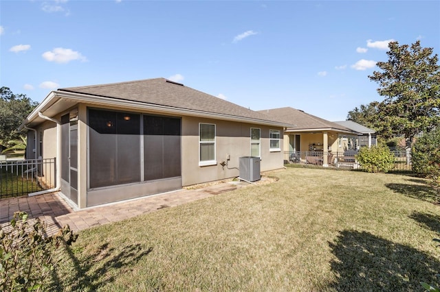 rear view of property featuring central AC unit, a sunroom, and a lawn