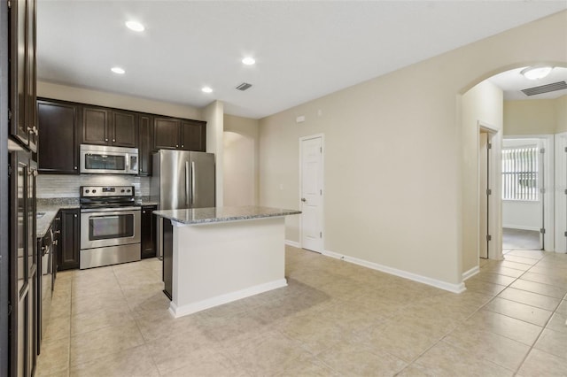 kitchen with light stone countertops, light tile patterned floors, stainless steel appliances, and a kitchen island