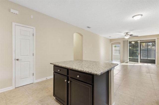 kitchen with ceiling fan, light tile patterned floors, a center island, and dark brown cabinets