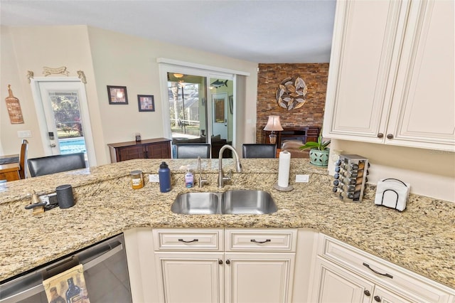 kitchen featuring white cabinetry, a large fireplace, sink, dishwasher, and light stone countertops