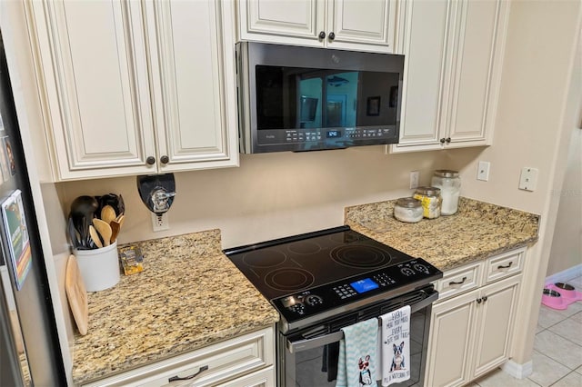 kitchen with white cabinets, light tile patterned floors, electric range, and light stone counters