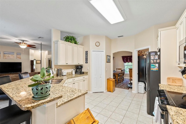 kitchen with light tile patterned flooring, sink, a breakfast bar area, appliances with stainless steel finishes, and kitchen peninsula