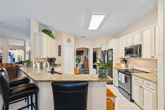 kitchen with sink, a breakfast bar, stainless steel appliances, light tile patterned flooring, and kitchen peninsula