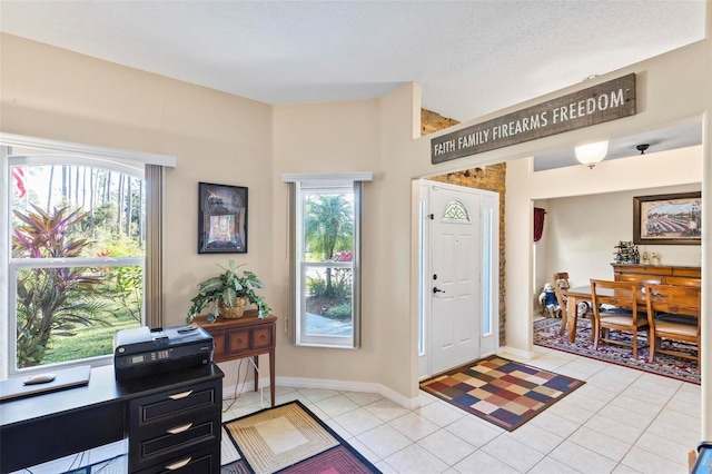 foyer entrance featuring light tile patterned flooring, a healthy amount of sunlight, and a textured ceiling