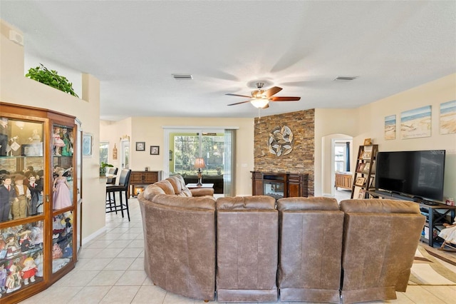 tiled living room featuring a textured ceiling, a fireplace, and ceiling fan