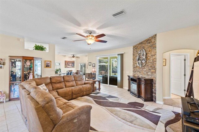 tiled living room with ceiling fan and a textured ceiling