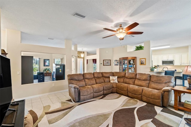 living room featuring light tile patterned flooring, ceiling fan, and a textured ceiling