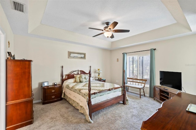 bedroom featuring ceiling fan, a tray ceiling, and light carpet