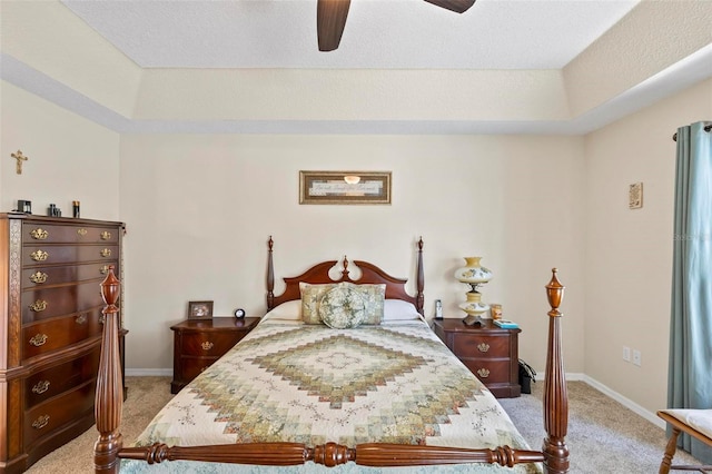 bedroom with a raised ceiling, ceiling fan, and carpet flooring