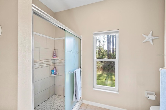 bathroom with tile patterned flooring, toilet, and tiled shower