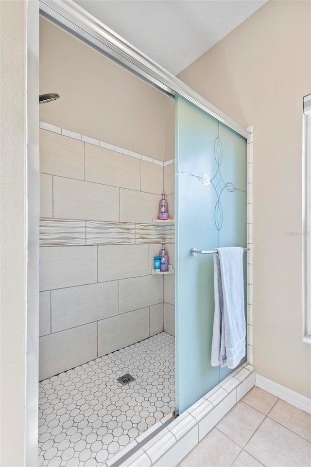 bathroom featuring tiled shower and tile patterned flooring