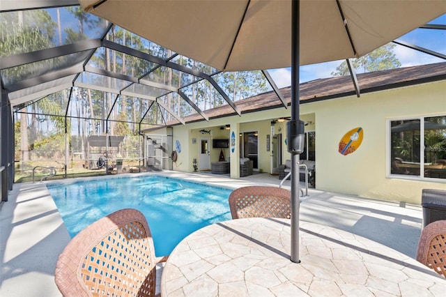 view of pool featuring a patio, ceiling fan, and glass enclosure