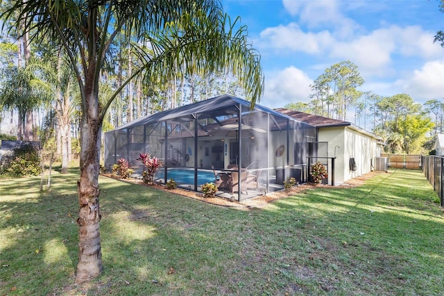 back of property featuring a lanai, a fenced in pool, and a lawn