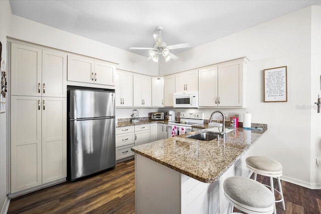 kitchen featuring kitchen peninsula, a kitchen breakfast bar, white appliances, and sink