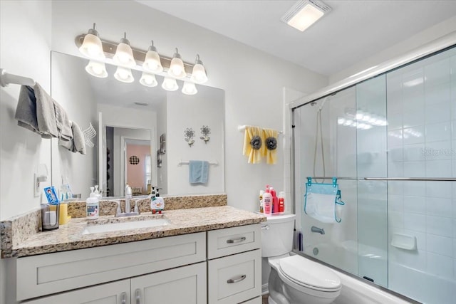 full bathroom with vanity, combined bath / shower with glass door, and toilet