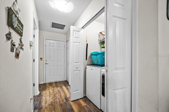 laundry room featuring a textured ceiling, washing machine and clothes dryer, and dark hardwood / wood-style floors