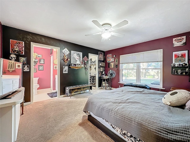 bedroom with ceiling fan, light carpet, and connected bathroom