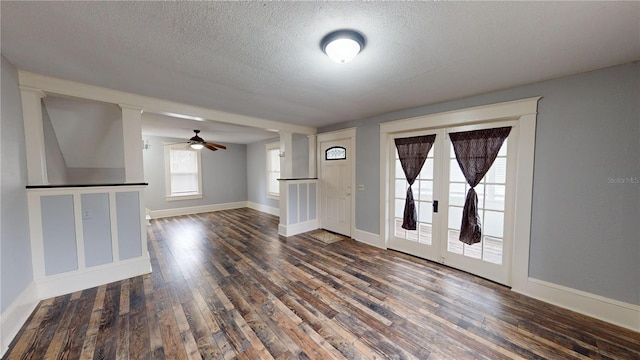 unfurnished living room featuring a textured ceiling, ceiling fan, and dark wood-type flooring