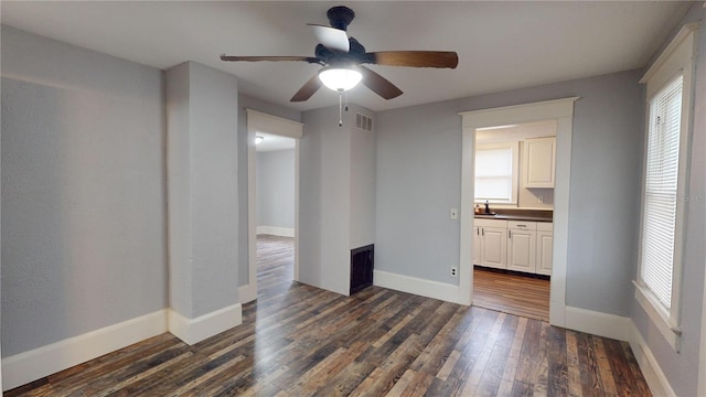 unfurnished bedroom featuring ceiling fan, sink, dark wood-type flooring, and ensuite bath