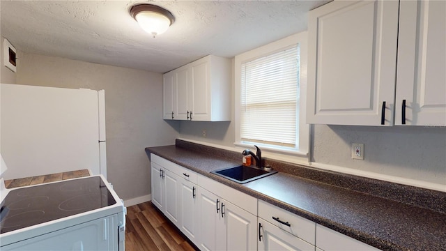 kitchen featuring white cabinets, stove, white fridge, and sink